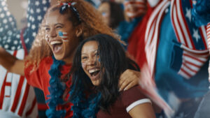 Two USWNT soccer fans dress in USA colors and cheer the women’s soccer team on at the 2024 Paris Olympics