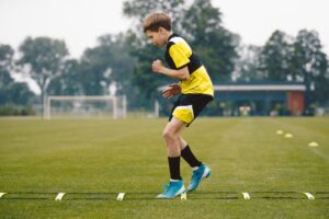 Young soccer player on a soccer field uses a training ladder for skipping, a youth soccer dynamic warm-up exercise