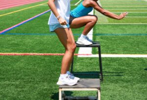 Two youth soccer players doing box jumps hops and other plyometric exercises on the field at practice  