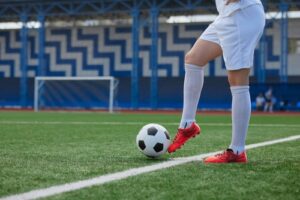 Female soccer player dribbles a soccer ball on a soccer field and thinks about the U.S. Women’s National Soccer Team