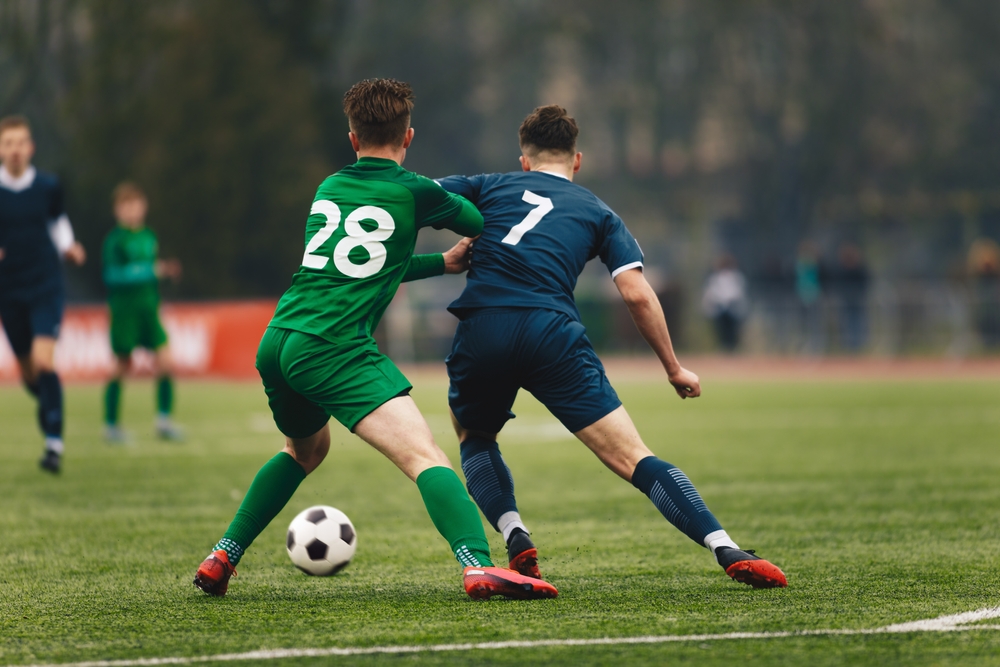 Two college soccer players attempt to gain control of the ball on a soccer field